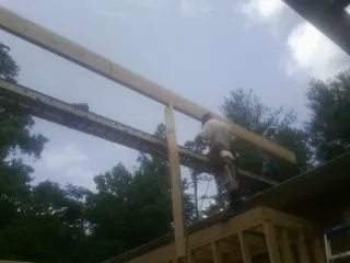Carpenter setting a ridge beam over a new addition frame — Ice Dam Removal by Roofing Brothers in De Borgia
