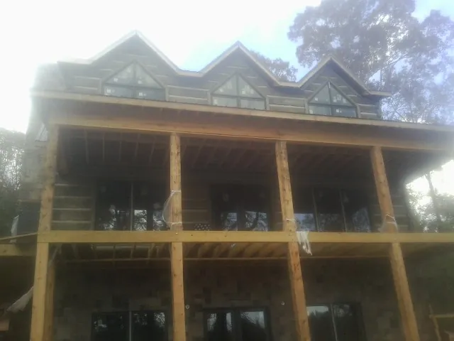 Dormers and porch framing on a large log home under construction — Roof Coating work by our crew in De Borgia