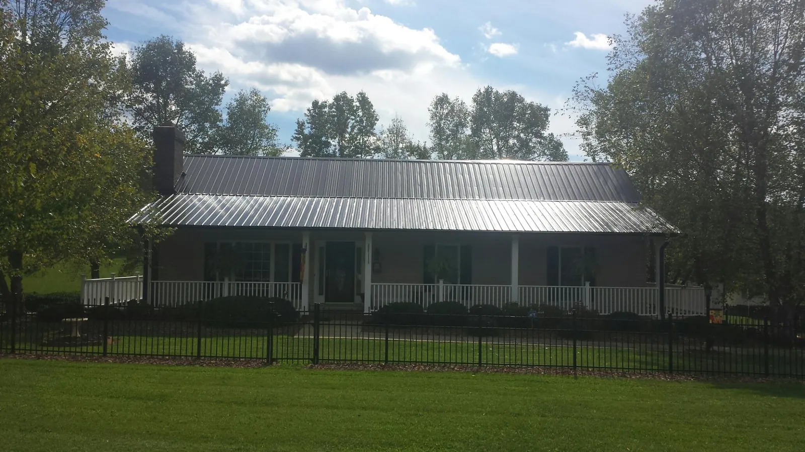 Gray metal roof on a brick ranch with a full width front porch — Gutter Guard Installation work by our crew in De Borgia